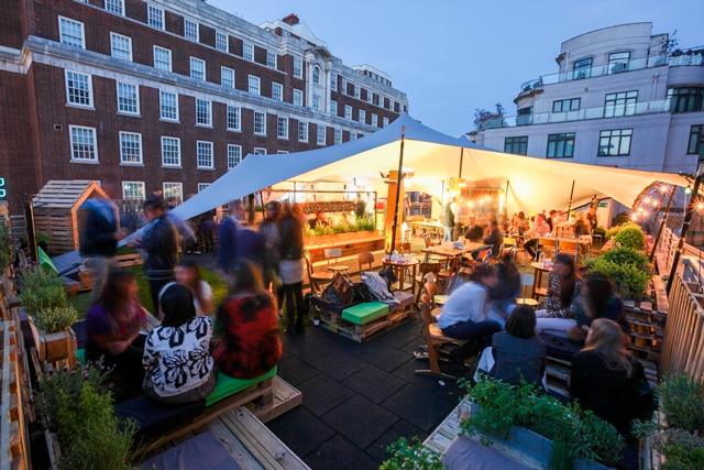 Rooftop pop-up at dusk with guests gathered under a stretch tent